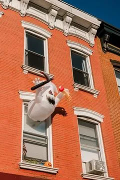 Inflatable ghost figure hangs from a window of a red brick building in the Stock Photos