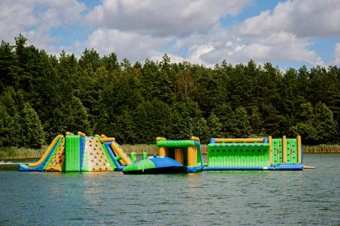 Inflatable obstacle course on lake with forest backdrop for summer fun. Weeke Stock Photos