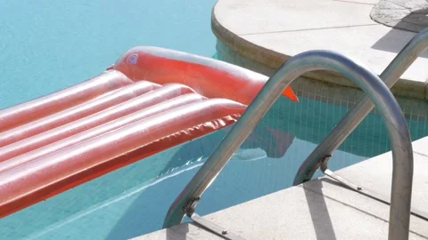 Inflatable orange air mattress floating on clear blue swimming pool water n.. Video stock 344032072