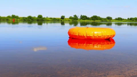 Inflatable orange circle on the surface of the river Stock Footage 220186071