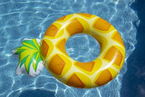 Inflatable pineapple ring floating in swimming pool Stock Photos