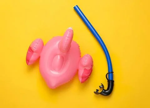 Inflatable pink flamingo pool float with snorkel on yellow background Stock Photos