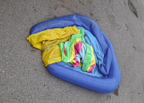 Inflatable pool discarded in trash after summer season ends, showcasing sig.. Stock Photos