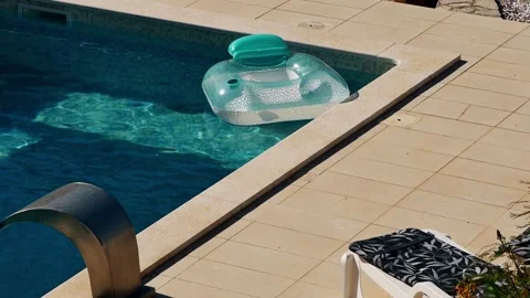 Inflatable pool floats in private villa pool during hot summer. Sunlight reflect Stock Footage 342328793