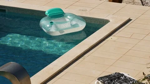 Inflatable pool floats in private villa pool during hot summer. Sunlight reflect Stock Footage 342328832