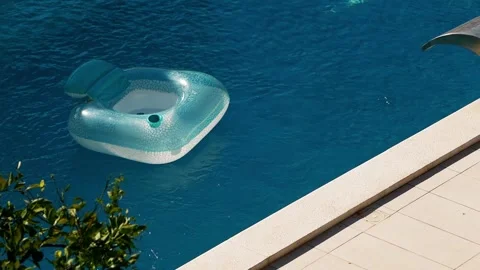 Inflatable pool floats in private villa pool during hot summer. Sunlight reflect Stock Footage 342328930