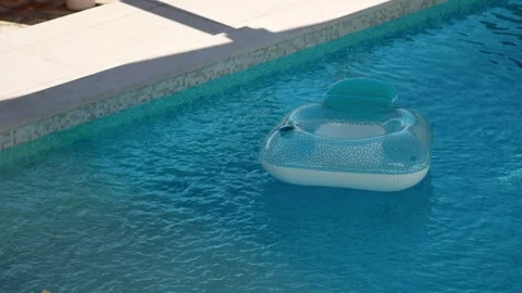 Inflatable pool floats in private villa pool during hot summer. Sunlight reflect Stock Footage 342328975