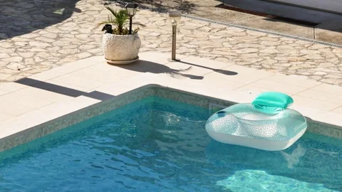 Inflatable pool floats in private villa pool during hot summer. Sunlight reflect Stock Footage 342329048