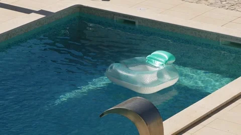 Inflatable pool floats in private villa pool during hot summer. Sunlight reflect Stock Footage 342329161