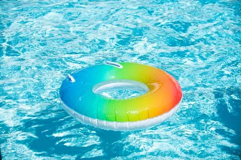 Inflatable ring floating in pool on summer background. Rainbow swimming pool 스톡 사진