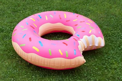 Inflatable swim ring in shape of donut on the grass. Summer vacations theme. Stock Photos