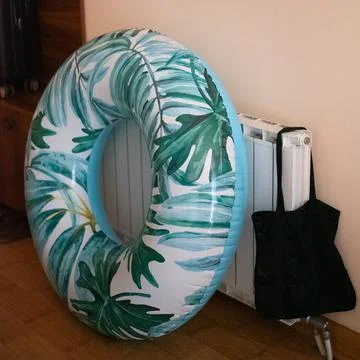 Inflatable swim ring with a tropical leaf pattern in home interior Stock Photos