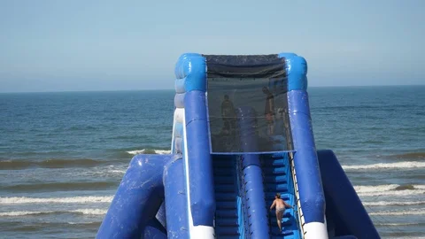 Inflatable Water slide on the Sandy beach in Europe. Summer warm day blue Sky. Stock-Footage 129382769