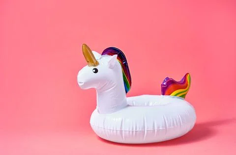 Inflatable white unicorn pool toy on pink background. Creative minimal concep Stock Photos