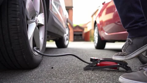 Inflating an SUV truck tire using a small red manual foot pump Video stock 162970956
