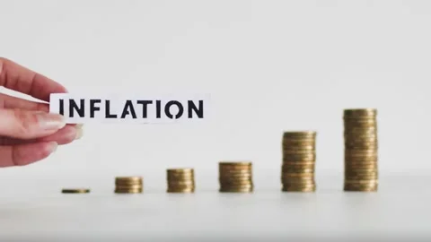 Inflation text in front of growing stacks of coins representing increasingly  Stock Footage 205282492