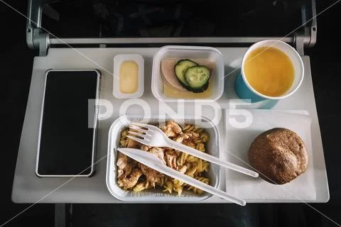 Inflight meal service tray for economy class, meat with pasta, seasoning frui Stock Photos