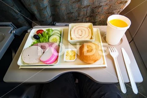 Inflight meal service tray for economy class, meat, fruit, salad, cucumber, a Stock Photos