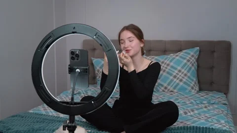 Influencer applying makeup while recording a tutorial video on bed Stock Footage 311779814