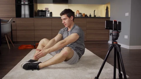 Influencer filming frog sit-up exercise at home Stock Footage 128757135