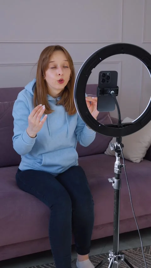 Influencer recording video content on smartphone with ring light at home Видео 314609189