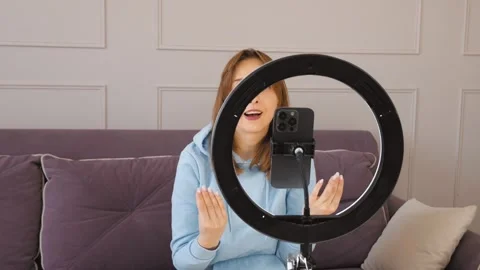 Influencer recording video content on smartphone with ring light at home Видео 314622294