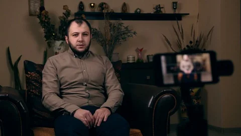 The influential Bearded Young guy, a blogger, of European appearance, sits in a Stock Footage 129375126