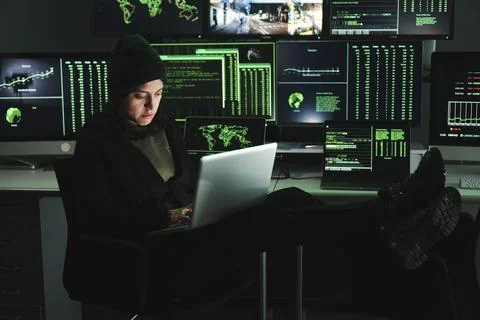 Informatic hacker woman typing code on laptop, at background a lot of computer Foto stock