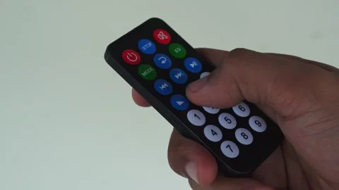 Infrared remote control with colorful buttons being pressed by a human hand Vídeo Stock 336438087