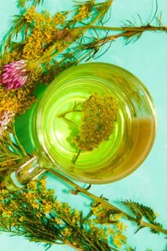 An infusion of useful herbs in a mug, next to a bouquet of wild flowers. Stock Photos