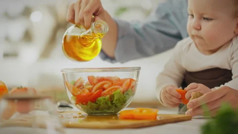 Ingredient. Caring parent using kitchen utensils adding oil to salad in home Stock Footage 278188528
