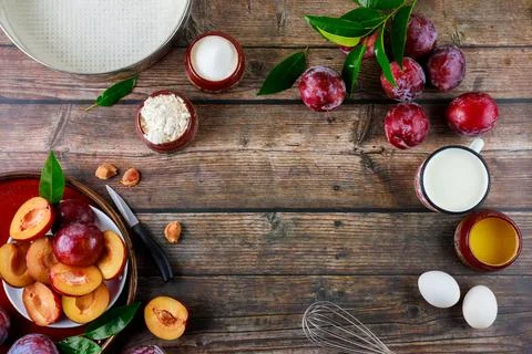 The ingredients of the baking process are eggs, whisk, plums, and a baking pan. Foto stock