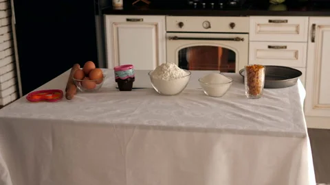 Ingredients for baking on the table with a white tablecloth-eggs, flour, sugar. Stock Footage 120840386