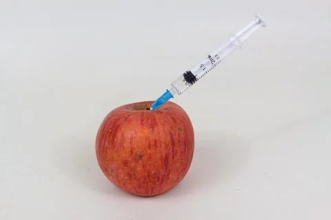 Injected apple with syringe inside closeup view isolated on white background Stock Photos