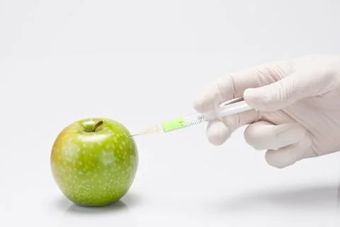Injecting a fluid into an apple. Stock Photos