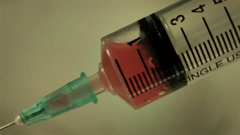 Injecting a red drug, using a needle and a plastic syringe Vídeo Stock 314137848