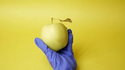 Injection into an apple, yellow background. Genetic modified foods. GMOs. Stock Footage 126990625