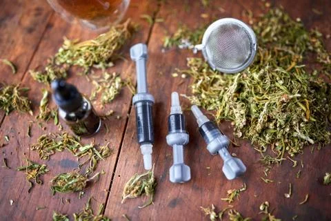 Injection of CBD oil, CBD paste, dried marijuana leaves on wooden background. Stock Photos