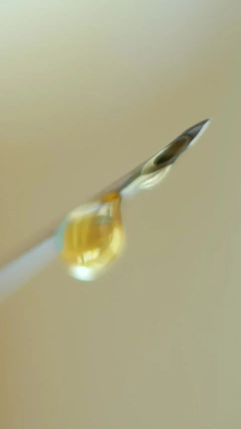 Injection needle with clear fluid drop reflecting light Stock Footage 320941113