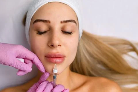 Injection procedure for lip augmentation, close-up. The cosmetologist slowly and Stock Photos