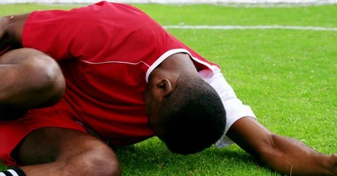 Injured football player lying on grass Stock Footage