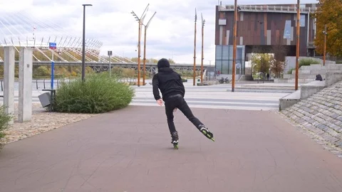 Inline skater in black doing stylish tricks on skates in slow motion Stockbeeldmateriaal 120445577