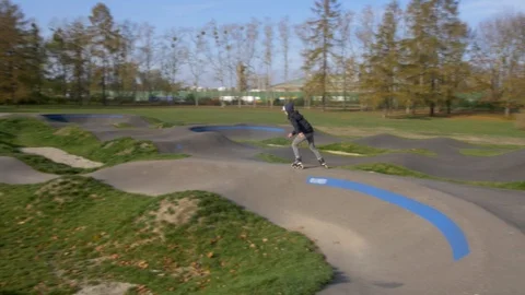 Inline Skater drops in Asphalt Pumptrack on Rollerblades Stockbeeldmateriaal 120445434
