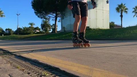 Inline skater gliding low angle along a paved urban path Stock Footage 345361737