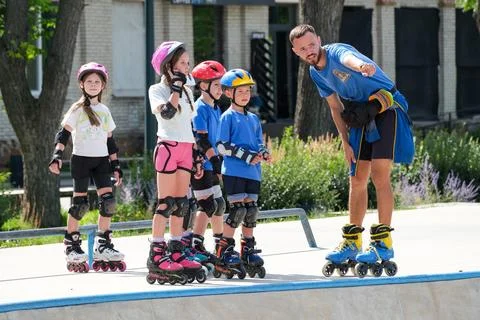 Inline skating coach instructing children at outdoor skatepark Stock Photos