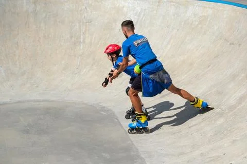 Inline Skating Coach Supporting Young Skater During Training Stock Photos