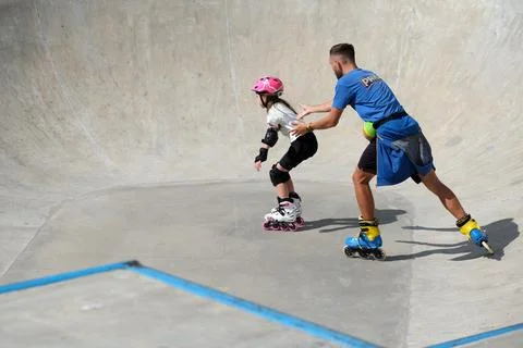 Inline skating instructor teaching young girl in skatepark Stock Photos