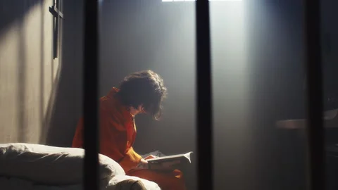 Inmate Reading Book while Sitting Alone in Prison Cell Stock Footage 310336358