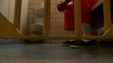 Inmate walking around jail cell with close up of shoes and orange jumpsuit. Stock Footage