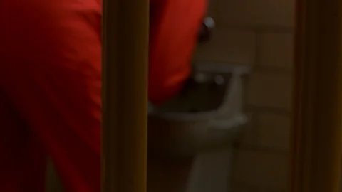 Inmate washes hands and face in jail cell and sits on edge of cot. Video stock 106413419